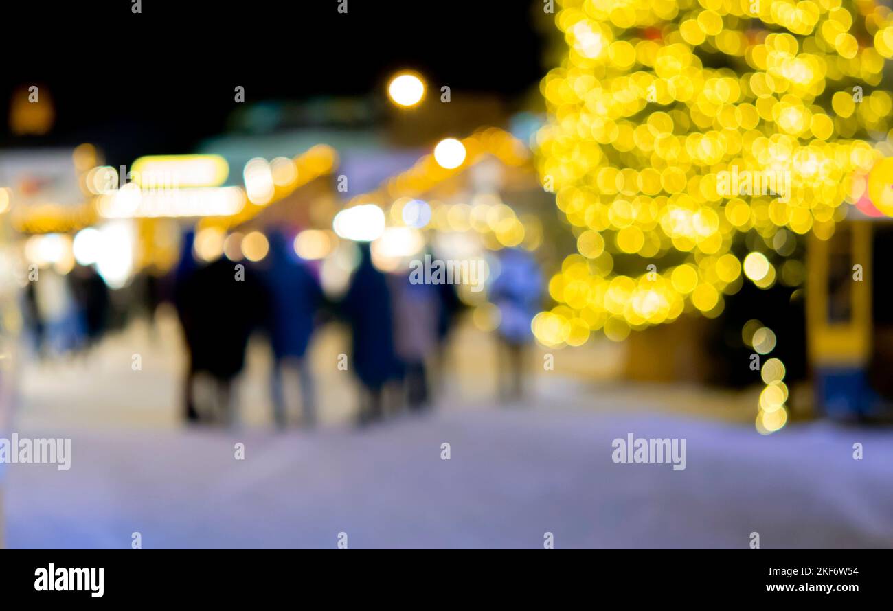 Sfondo sfocato. Albero di Natale, luci decorate, edificio, sagome sfocate di persone che camminano piazza della città durante la notte d'inverno. Bello Capodanno e Natale vacanza sfondo sfocato Foto Stock
