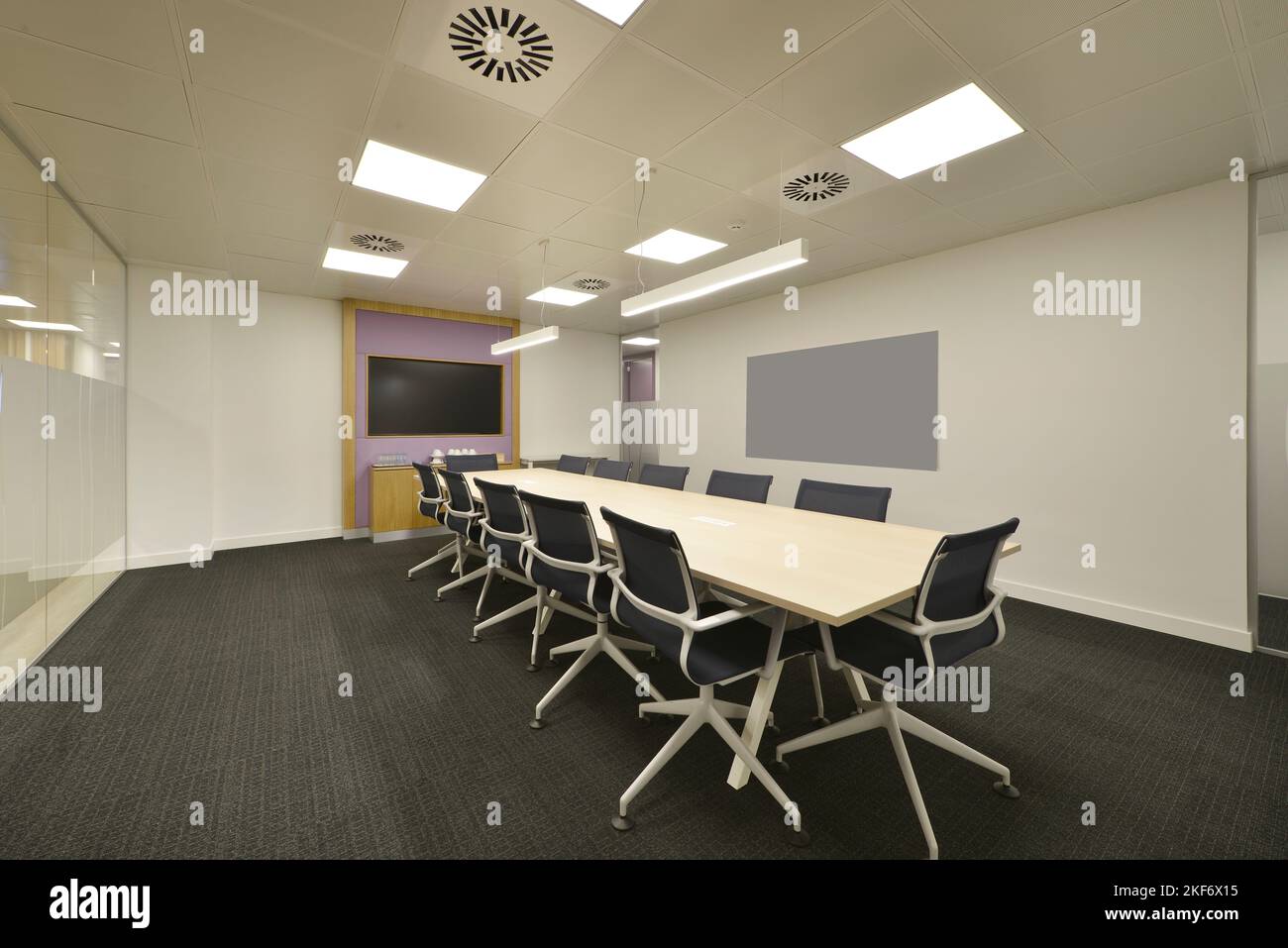 Sala riunioni di un ufficio coworking con sedie girevoli e lungo tavolo in legno di faggio Foto Stock