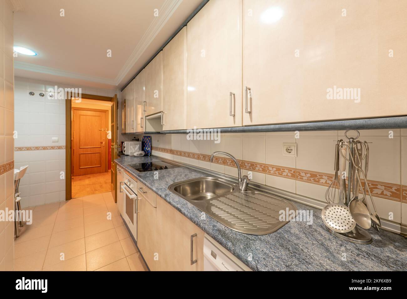 Cucina con armadi in legno color crema con ripiani blu e elettrodomestici bianchi da incasso Foto Stock