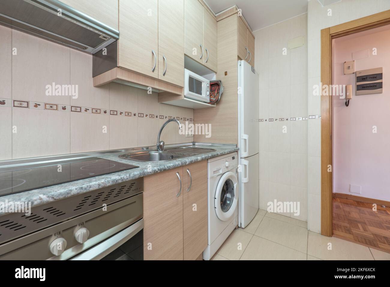 Cucina con armadi in legno chiaro e elettrodomestici bianchi integrati Foto Stock