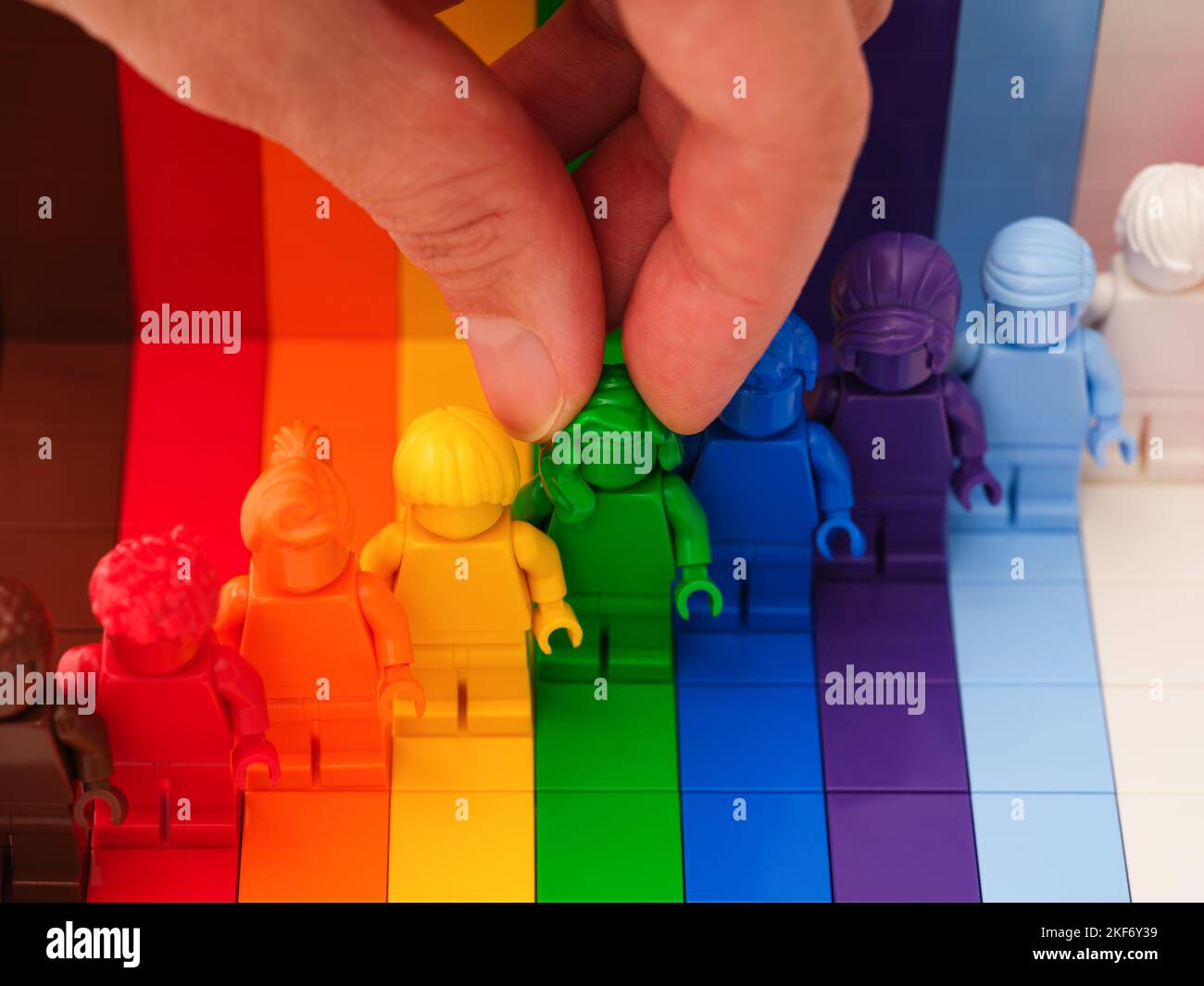 Tambov, Federazione Russa - 09 novembre 2022 Una mano donna che prende una minifigura verde Lego da una fila di altre minifigure arcobaleno. LEGO Everyone è Un Foto Stock