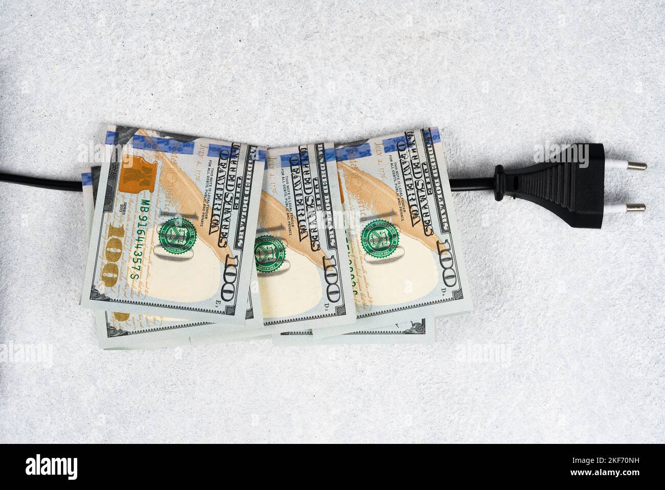 Spina nera e molte banconote da 100 dollari sul cavo elettrico. Aumento dei prezzi dell'elettricità nel mondo. Costi energetici elevati, energia mondiale e po Foto Stock