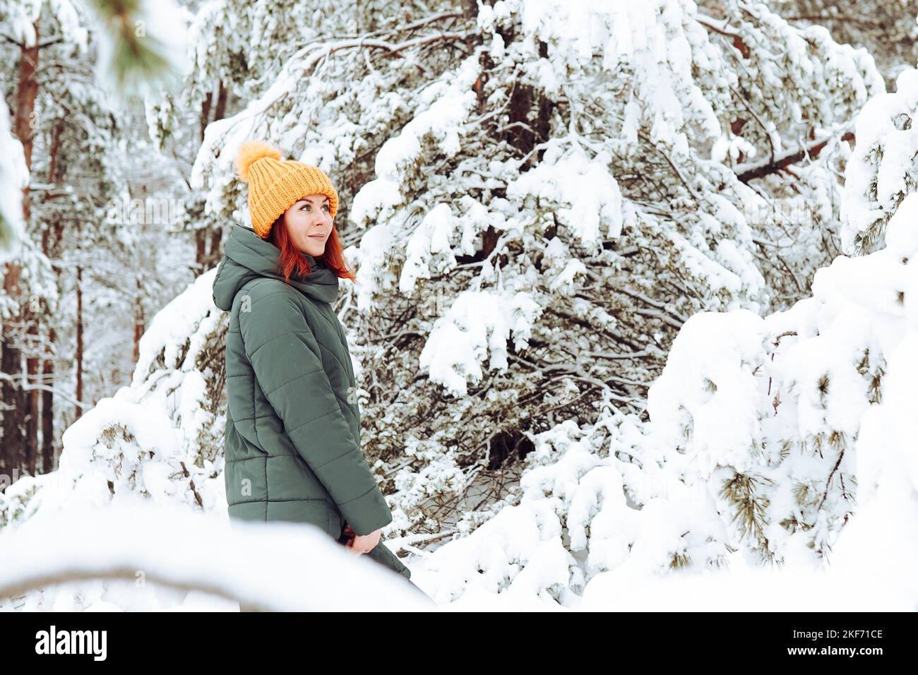 Ragazza allegra in abiti caldi giocando con la neve all'aperto vicino alla bella foresta Foto Stock