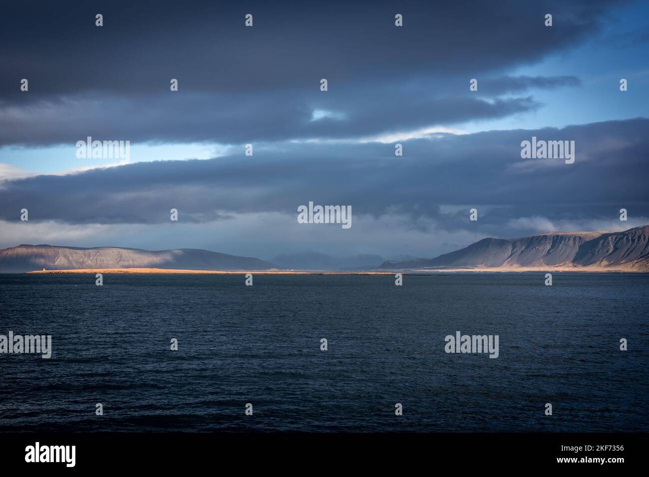 Paesaggio con il Monte Esja e la costa dell'oceano Atlantico a Reykjavik, Islanda. Non c'è gente, cielo nuvoloso blu. Foto Stock