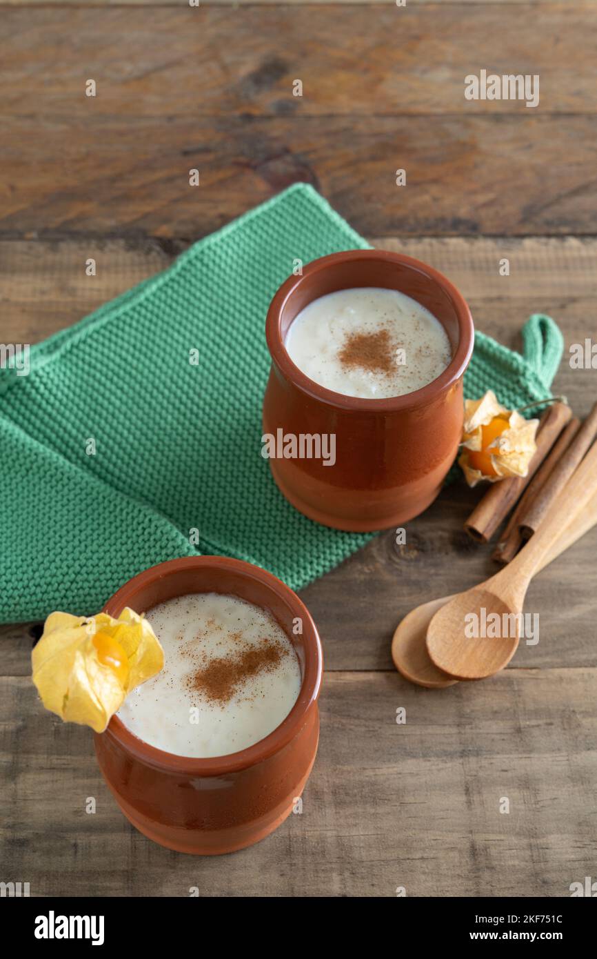 Ciotole in ceramica di budino di riso e cannella con decorazione su fondo in legno con cucchiai e straccio di tovagliolo. Spazio di copia. Foto Stock