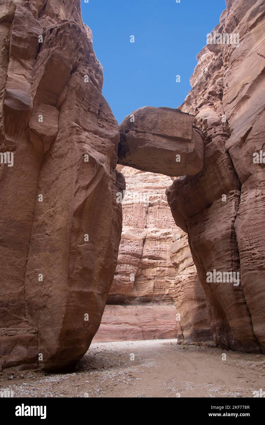 Enorme roccia sospesa tra due lati di un canyon Wadi Numeira Giordania Foto Stock