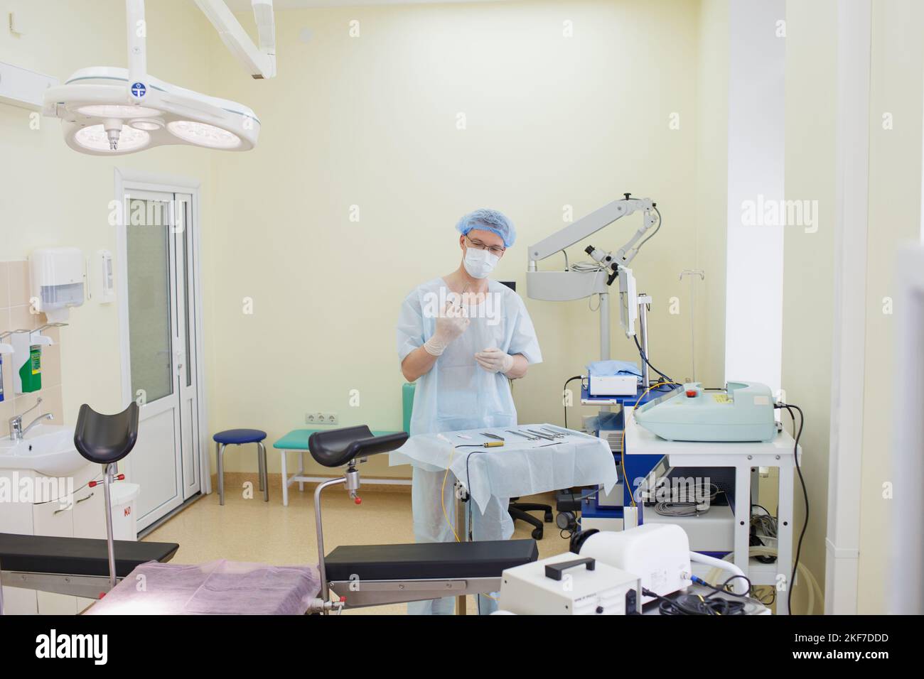 Un medico di sesso maschile che prende uno strumento chirurgico per un gruppo di chirurghi in background nella sala operatoria. Strumenti medicali in acciaio, pronti all'uso. Il Foto Stock