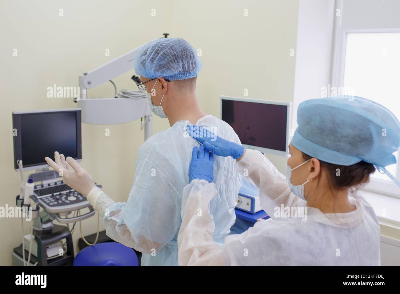 Il chirurgo si sta preparando all'intervento chirurgico. Un assistente aiuta un chirurgo esperto a indossare abiti sterili prima dell'intervento chirurgico. Foto Stock