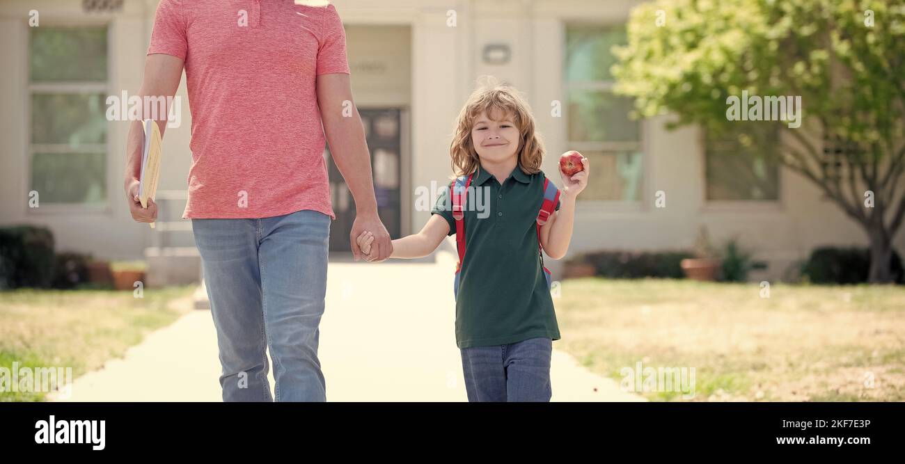 Banner di bambino di ritorno a scuola, felice famiglia di capretto e padre con mani di mela tenere che conduce al primo grado di scuola, scuola Foto Stock
