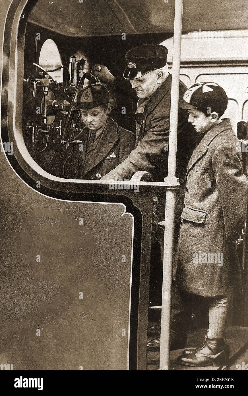 1930's immagine di due scolari britannici sulla pedana di un motore a vapore. Foto Stock