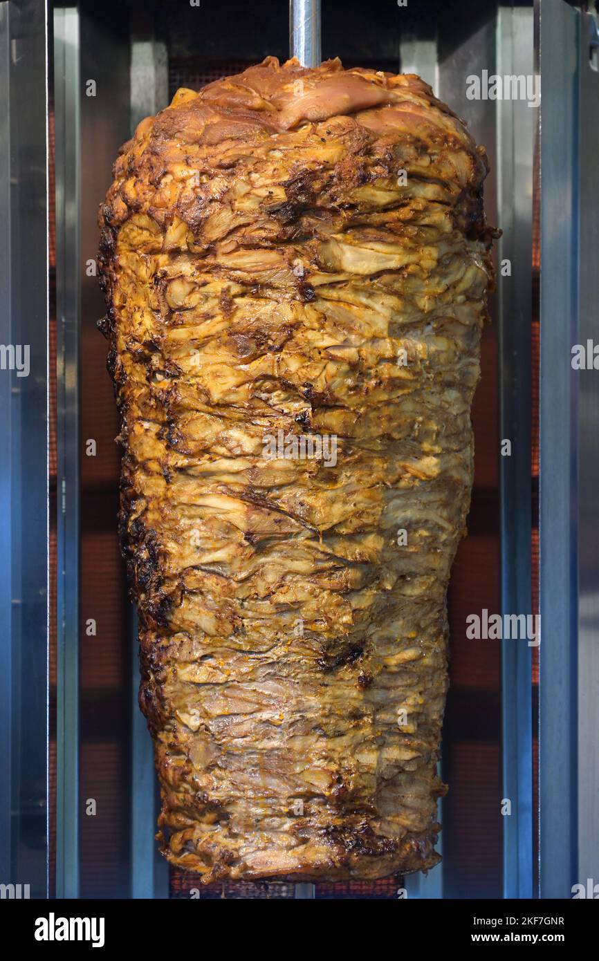 Griglia verticale con carne a strati per kebab o gyros, fast food per strada, focus selezionato Foto Stock