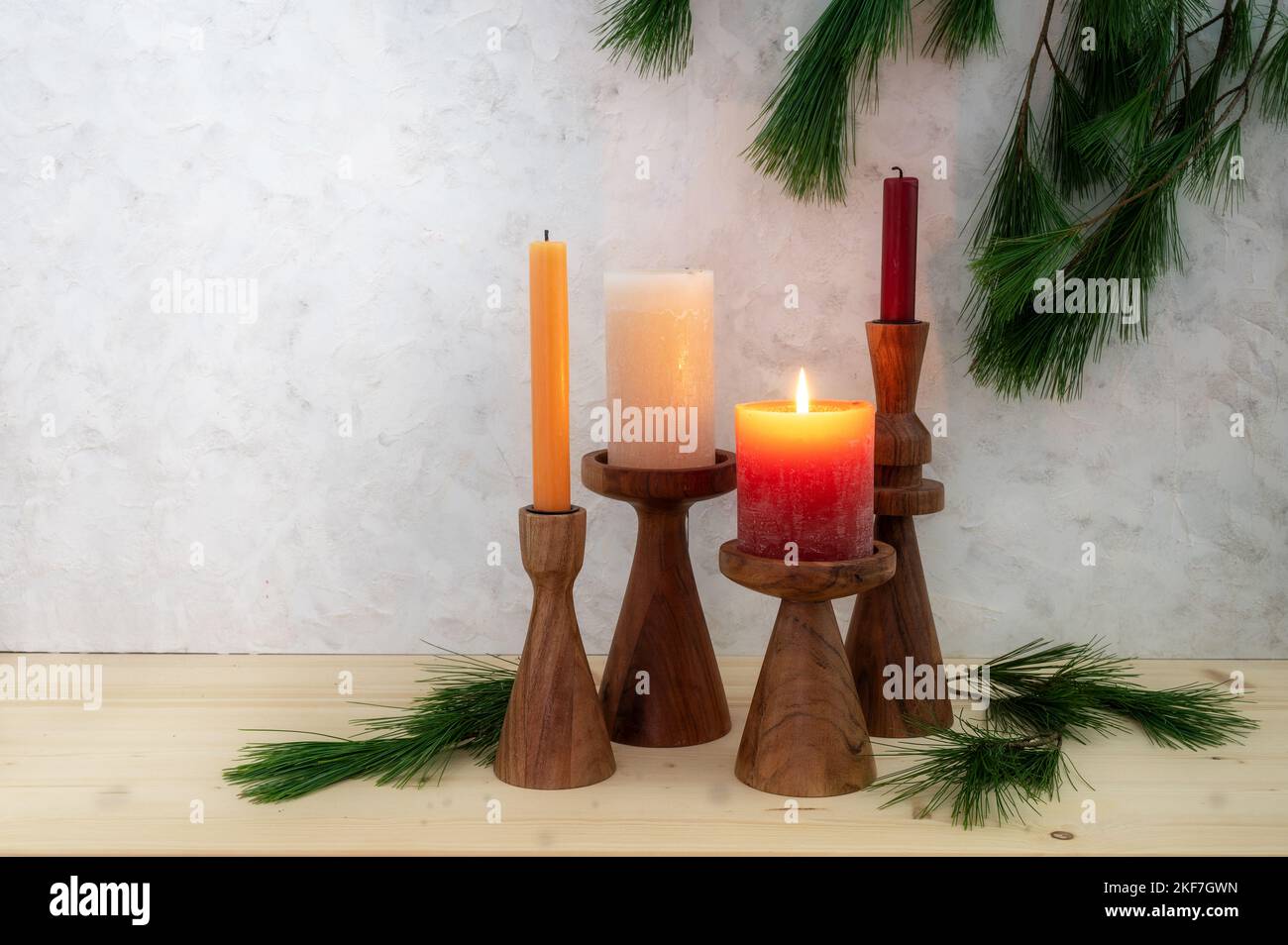 Quattro candele su stand di legno, uno è acceso per il primo Avvento, decorazione di rami di pino, legno chiaro e sfondo rustico in gesso, spazio copia, Foto Stock