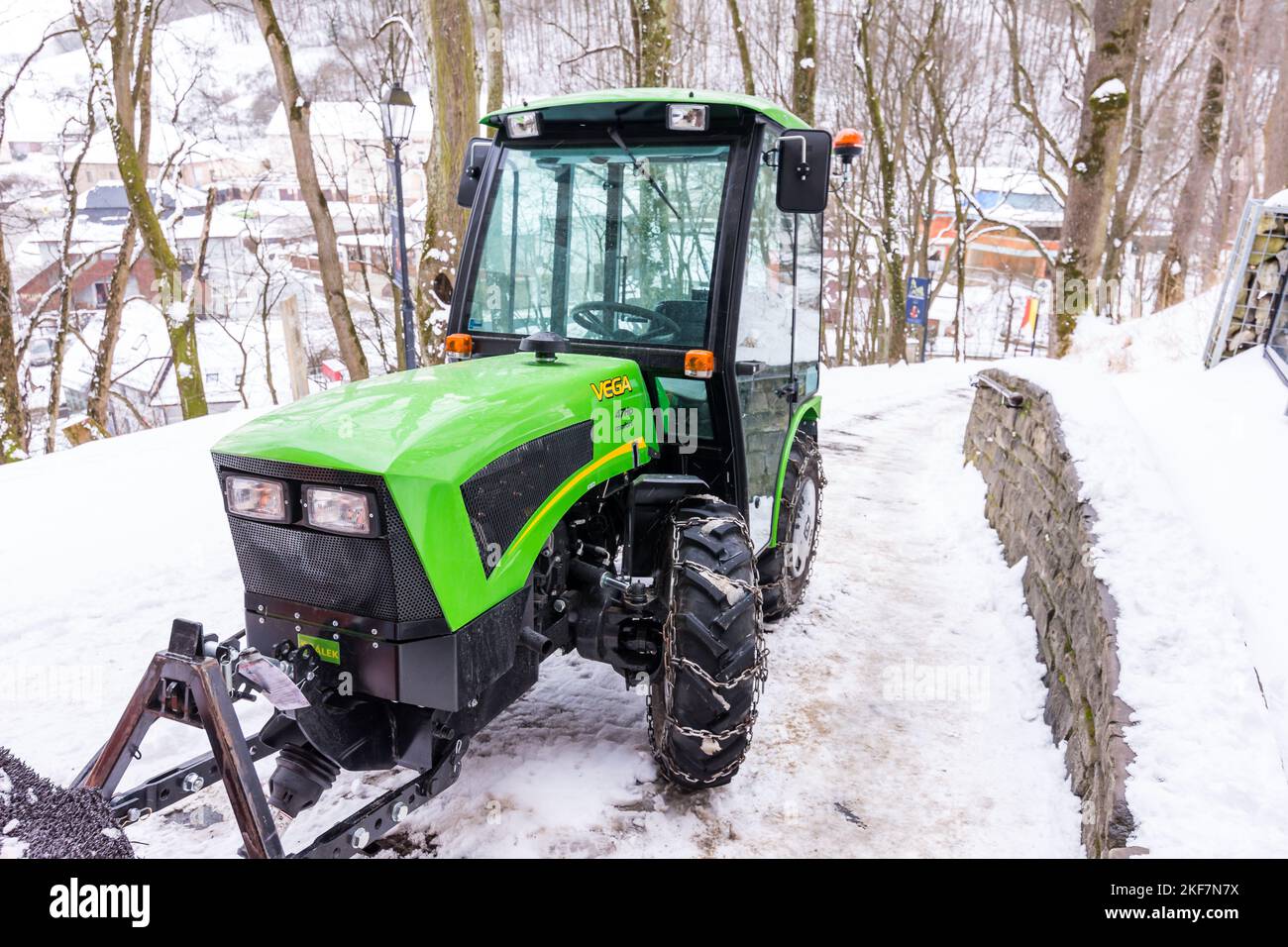 Piccolo trattore verde sulla neve, inverno e gelo. Foto Stock