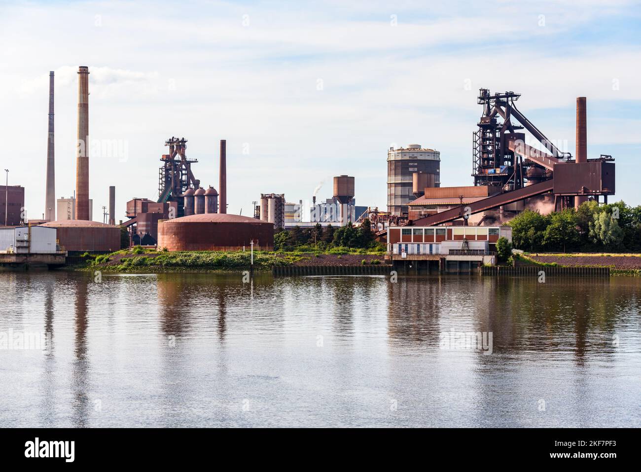 Vista di una acciaieria sulla riva di un fiume in una giornata estiva poco nuvolosa Foto Stock