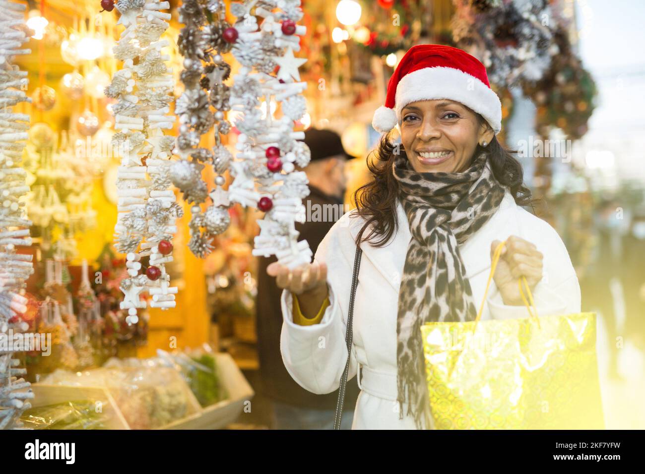 Donna che passa il tempo alla fiera e l'acquisto a mano decorazioni di Natale Foto Stock