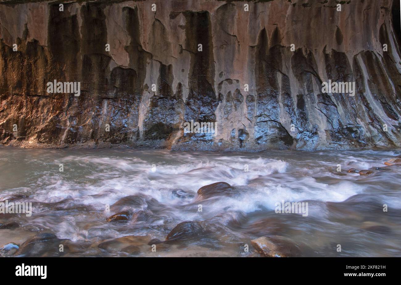 Piccola cascata sotto le scogliere a strapiombo con macchie minerali, Narrows of the Virgin River, Zion National Park, Utah Foto Stock