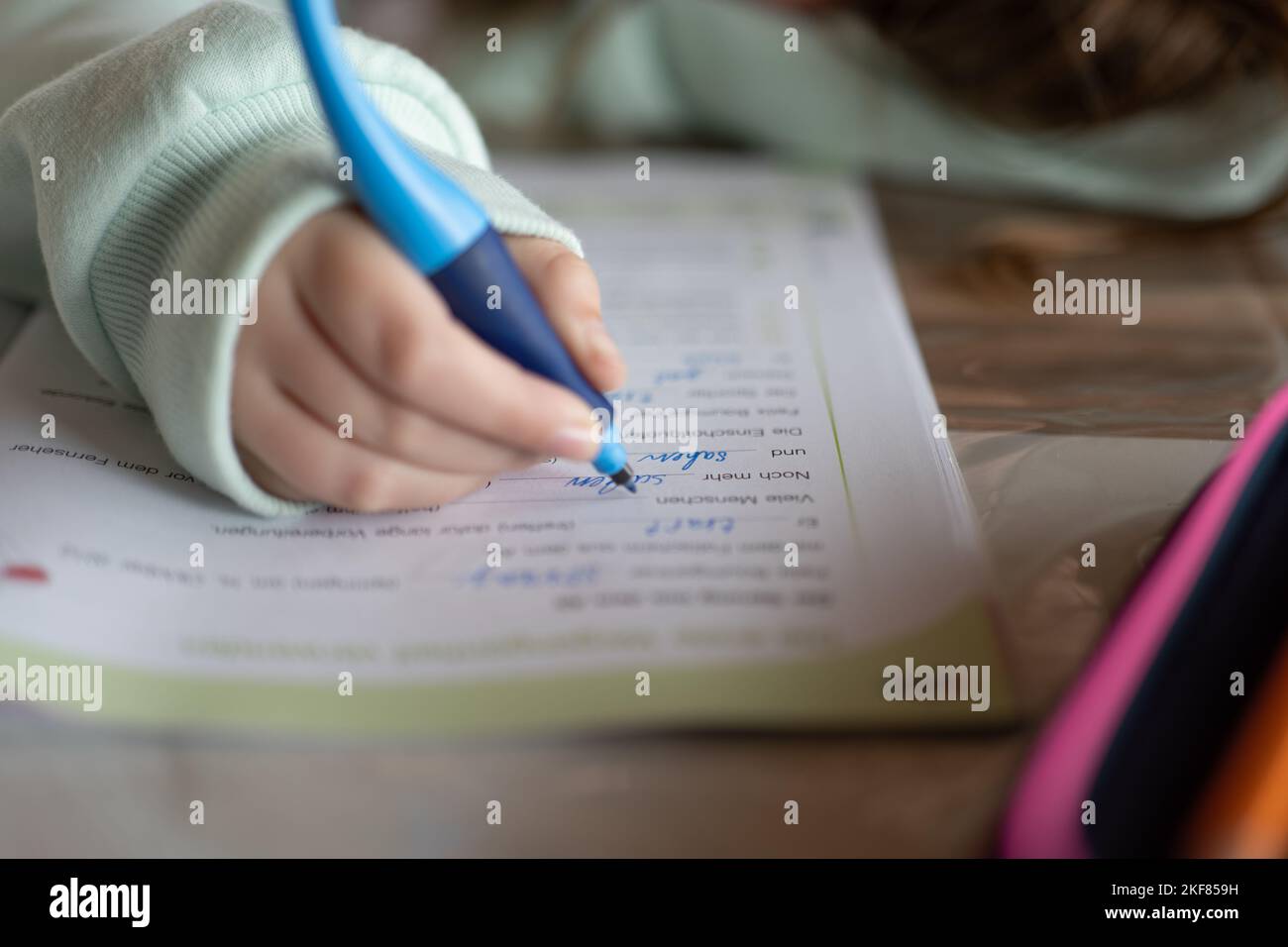 Studio e Education.schoolgirl fa il suo lavoro. Il bambino scrive con una matita in un taccuino.la matita di primo piano in una mano del childs. Foto Stock