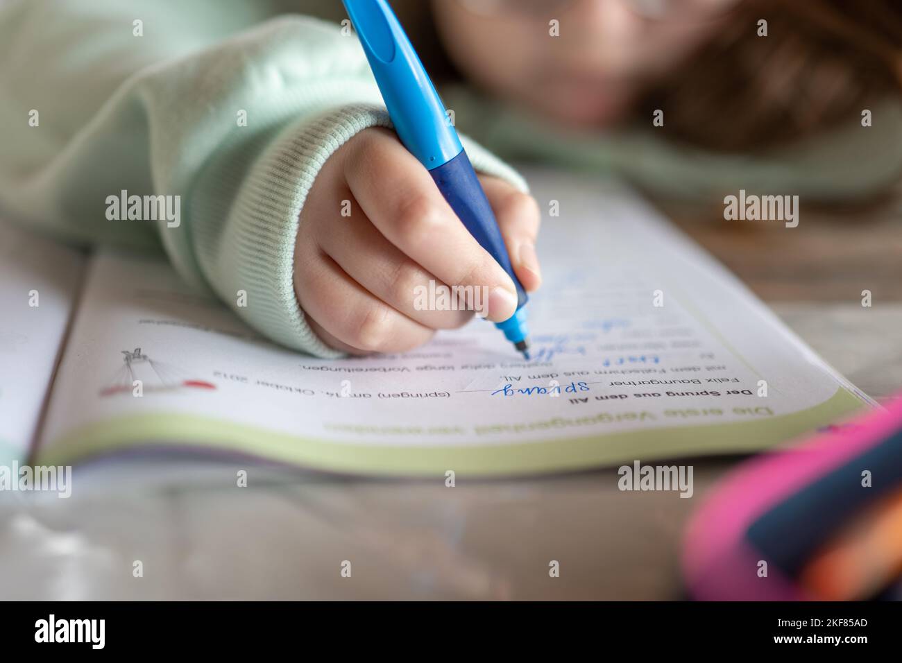 Homewwork.schoolgirl fa il suo lavoro. Il bambino scrive con una matita in un taccuino.primo piano matita in un bambino mano.Studio ed educazione Foto Stock