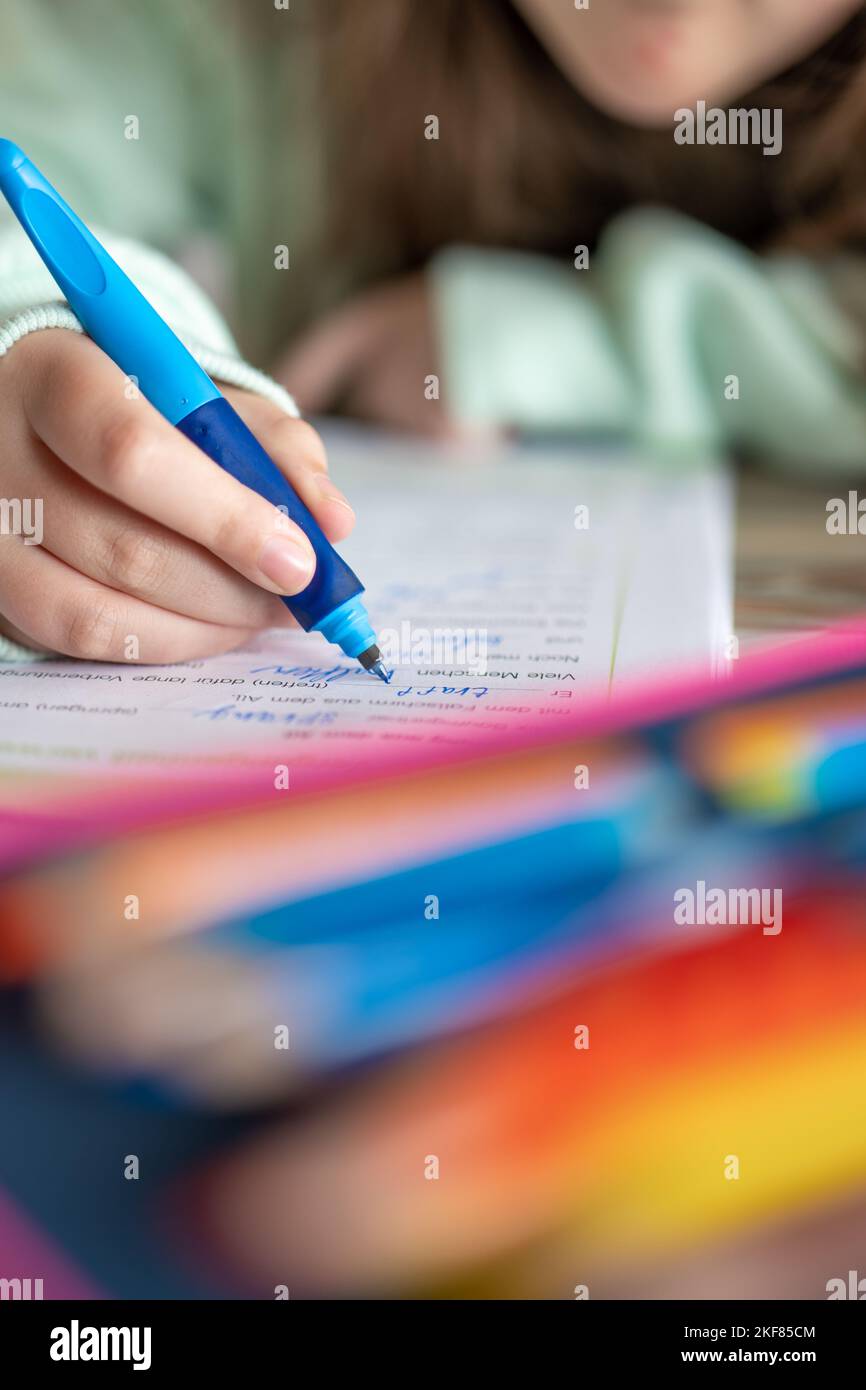 La ragazza in una felpa verde scrive le parole in un taccuino.Studio ed educazione.Schoolgirl fa il suo lavoro. il bambino scrive con una matita in un taccuino. Foto Stock