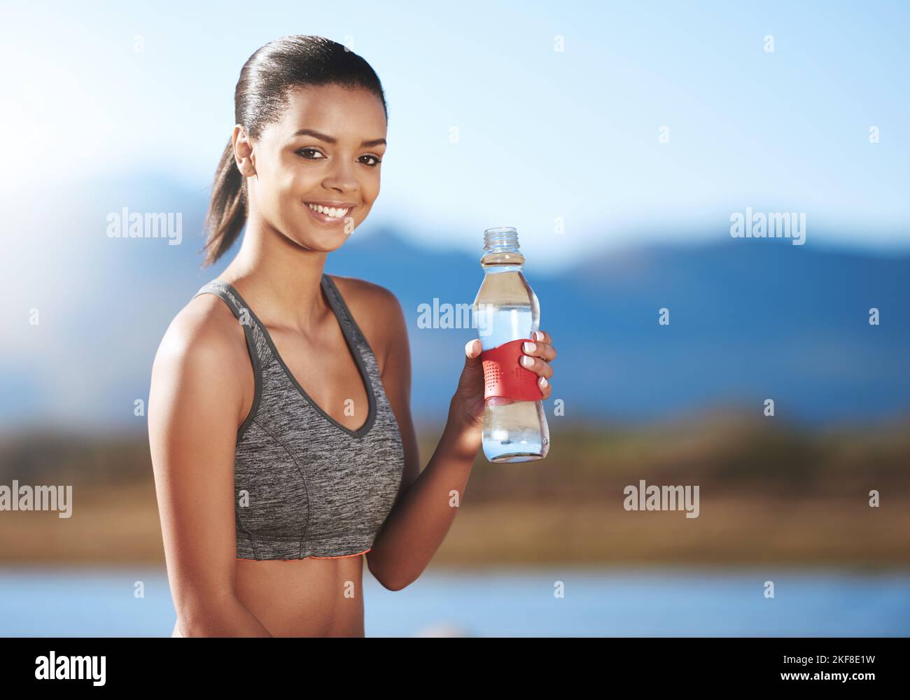 La felicità non è una destinazione, il suo stile di vita, una giovane donna sportiva che tiene la sua bottiglia d'acqua. Foto Stock