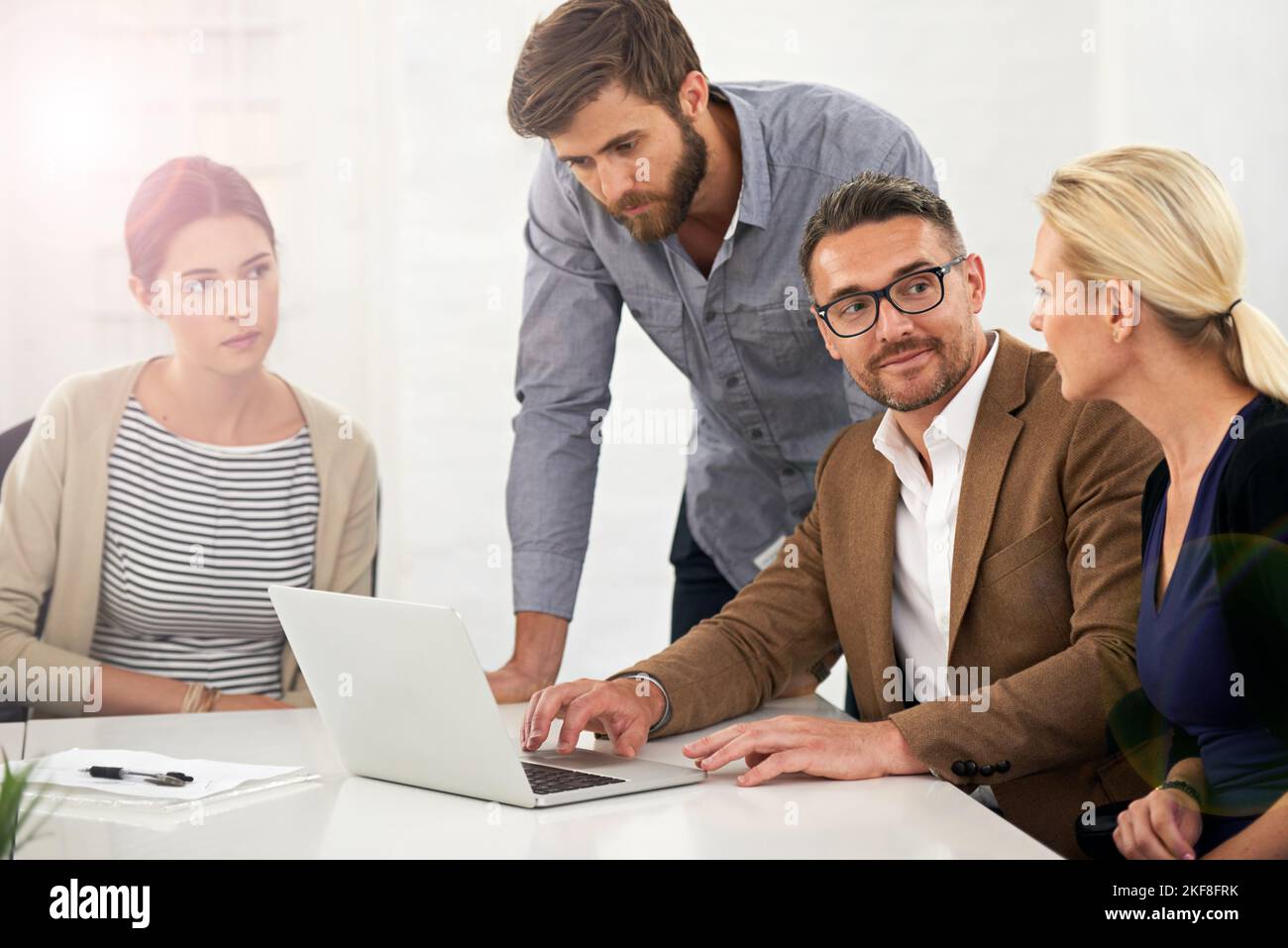 Rimbalzare le idee l'una dall'altra. Un gruppo di uomini d'affari che guarda al lavoro su un computer portatile in una riunione. Foto Stock