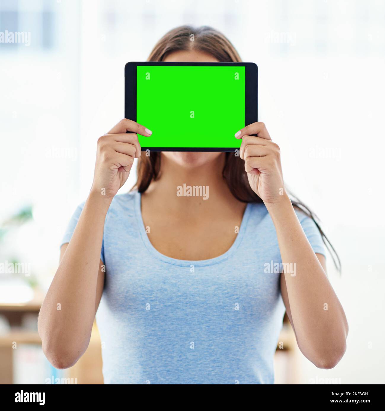 Guarda questa fantastica app. Una donna che tiene un tablet digitale con una schermata di tasti croma davanti al viso. Foto Stock
