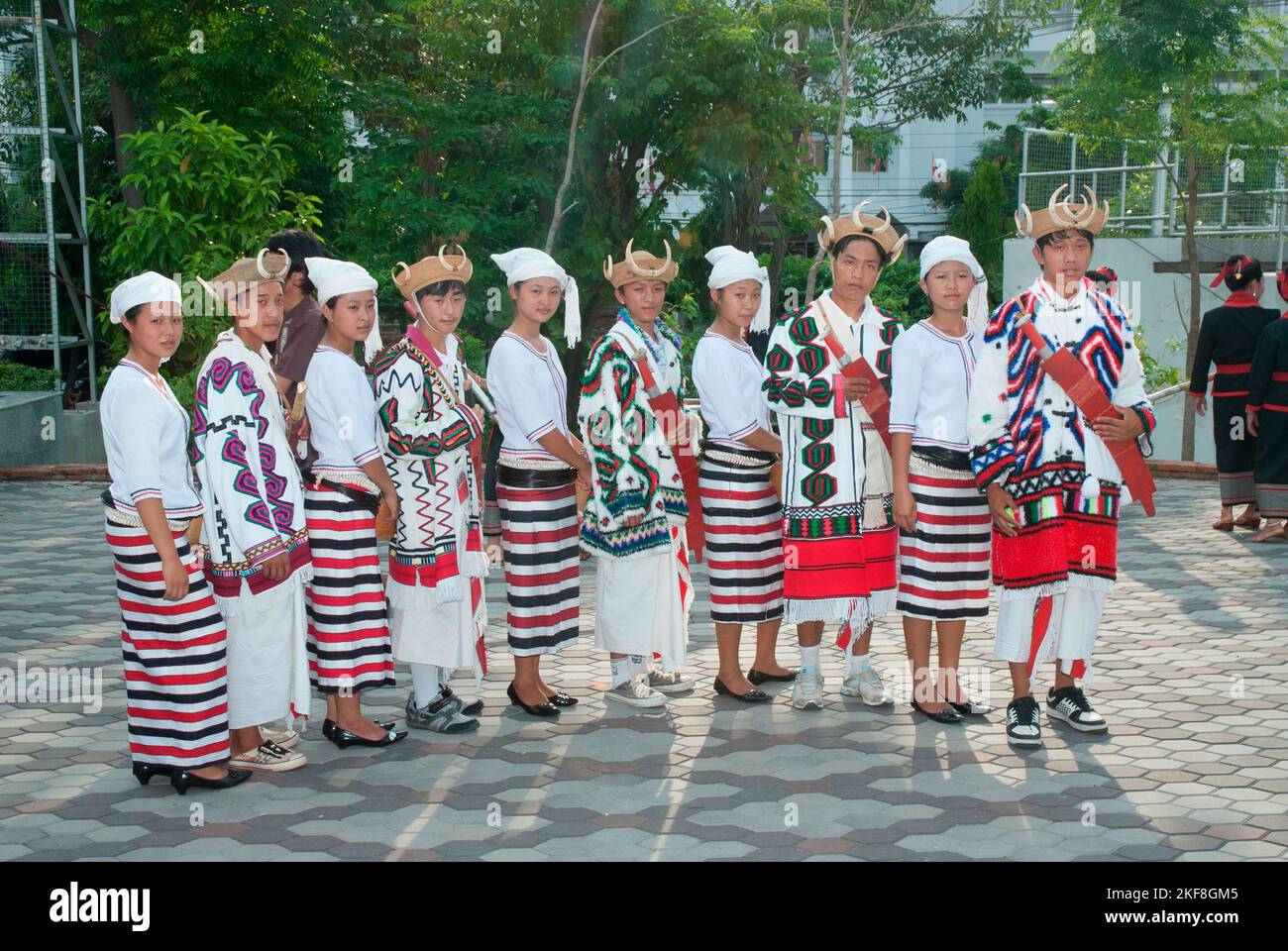 Etnico Kachin maschio in abbigliamento tradizionale indossare tradizionali cappelli di rattan con zanghe di cinghiale e ragazze in bianco headdress durante uno spettacolo culturale nazionale. Foto Stock