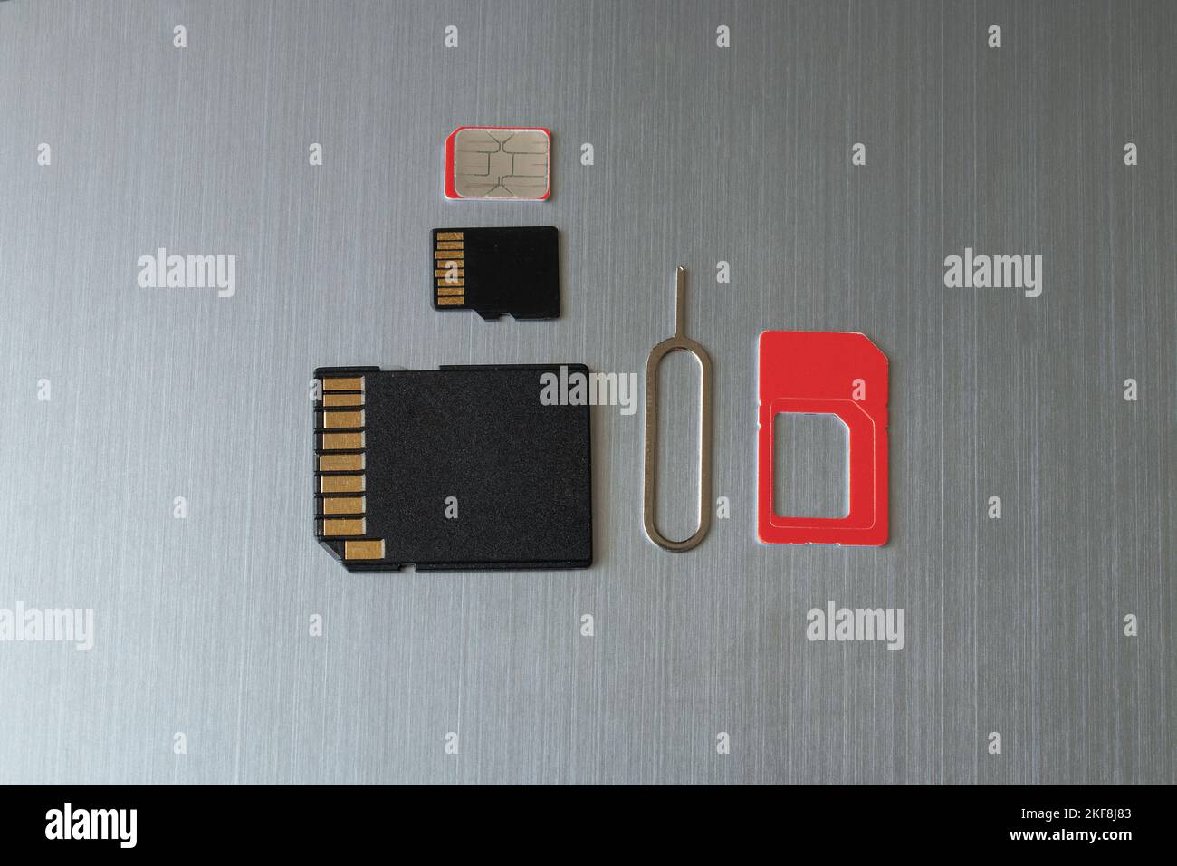 La scheda SIM e la graffetta per aprire lo slot della scheda SIM e la scheda di memoria si trovano su uno sfondo grigio in acciaio Foto Stock