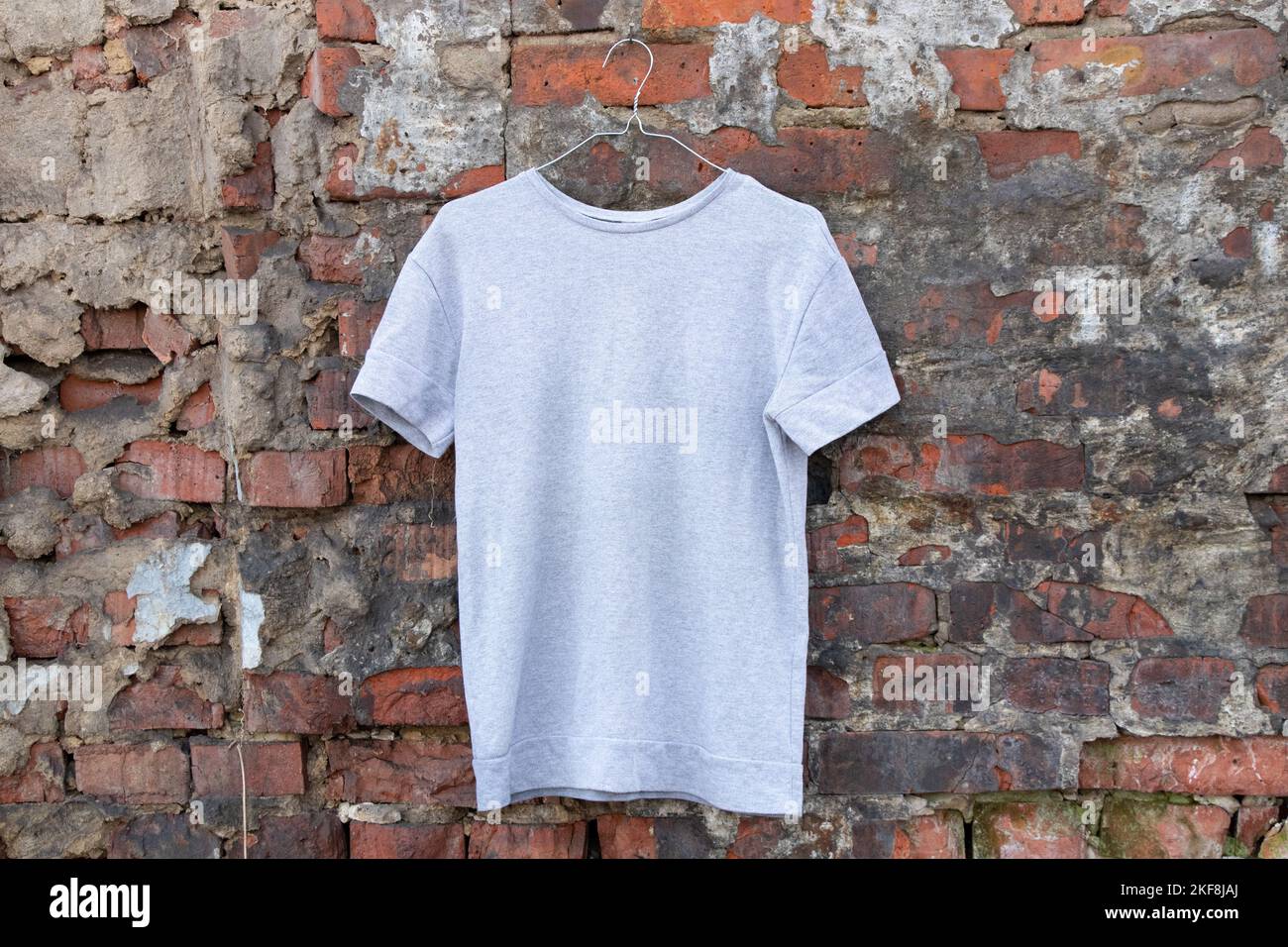 maglione leggero appeso a un appendiabiti su una parete di mattoni sulla strada, abbigliamento femminile di moda Foto Stock