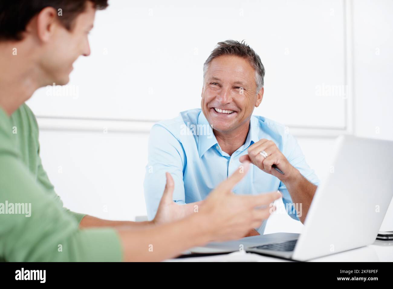 Un sano scambio di idee. Un dirigente maturo che si è posto sopra un lavoro su un notebook con un collega più giovane. Foto Stock