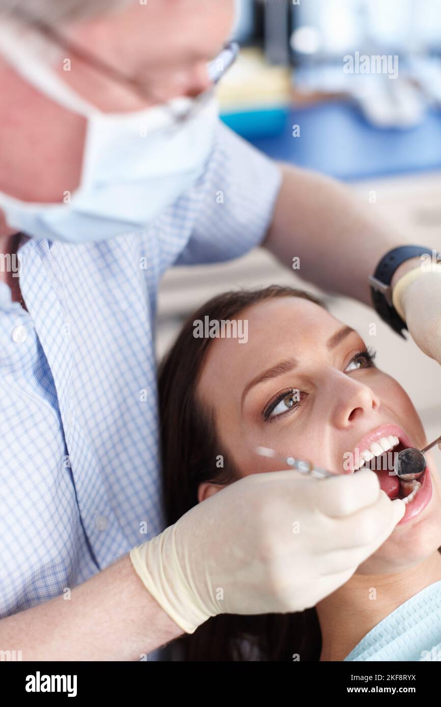 Controllo dentale. Vista ad angolo elevato del dentista che pulisce i denti del paziente. Foto Stock