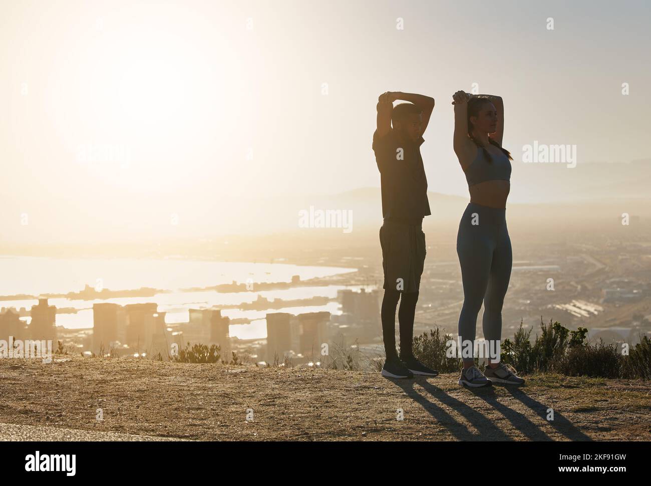 Fitness, silhouette e coppia si allungano in città al mattino per motivi, ispirazione e benessere. Sport, esercizio fisico e allenamento uomo e donna Foto Stock