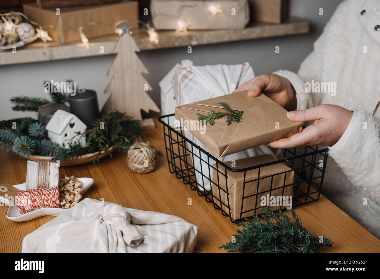 Confezioni regalo di carta kraft e furoshiki in tessuto eco-friendly. Regali di Natale sfondo di natale con le mani femminili con carta kraft e Furoshiki Foto Stock
