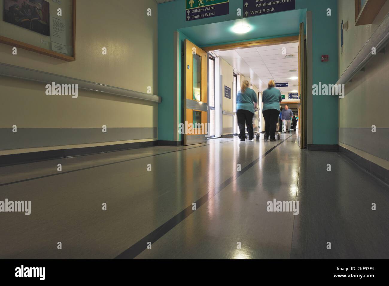 Due addetti alle pulizie mediche attraversano un corridoio ospedaliero con attrezzature Foto Stock