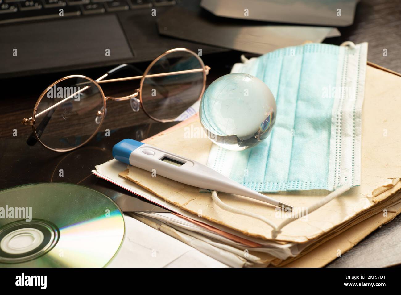 termometro a disco globo scheda e maschera medica e computer portatile si trovano sulla scrivania del medico in ufficio, medicina globale, scrivania del medico, trattamento online e d Foto Stock