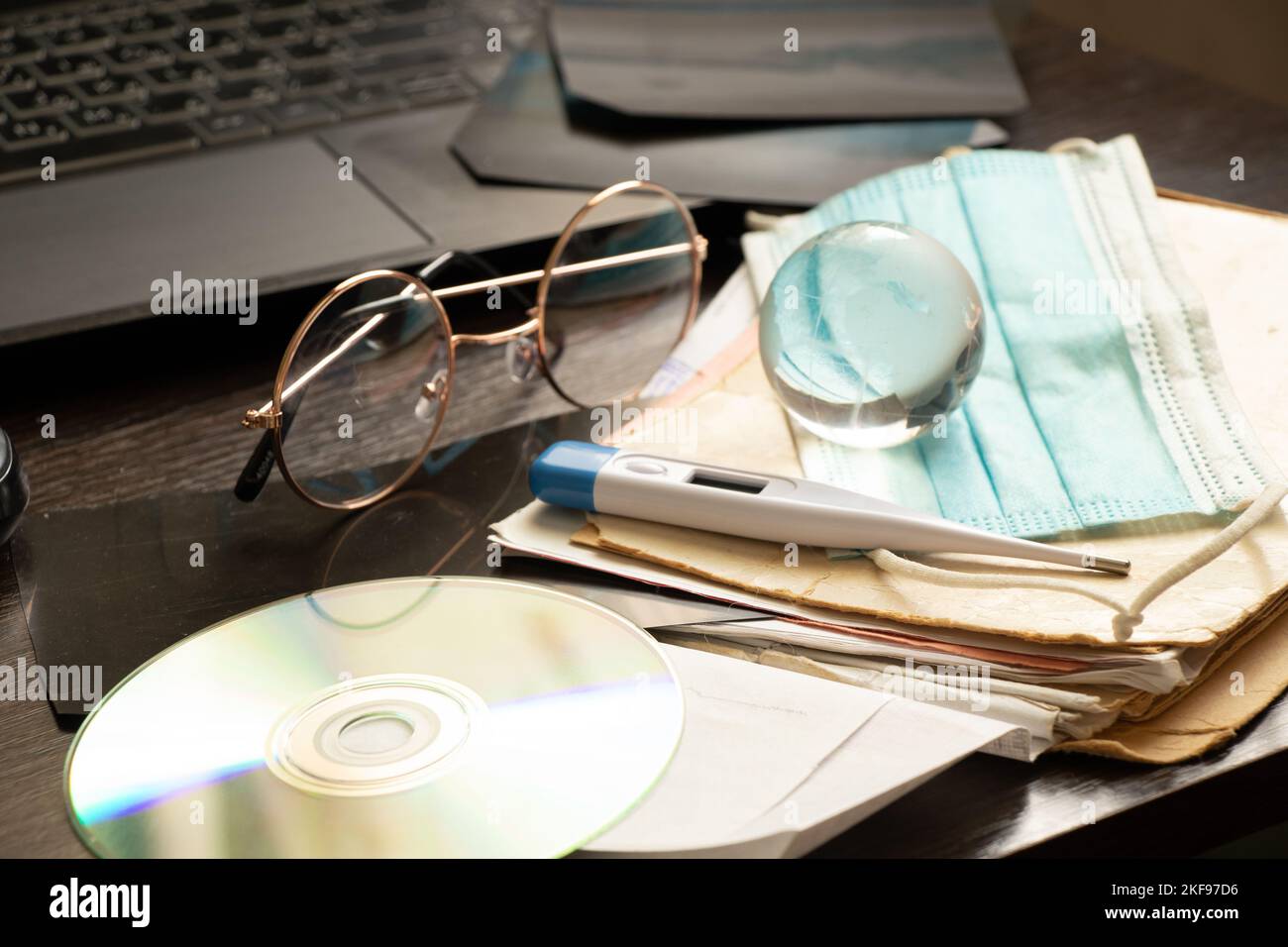 termometro a disco globo scheda e maschera medica e computer portatile si trovano sulla scrivania del medico in ufficio, medicina globale, scrivania del medico, trattamento online e d Foto Stock