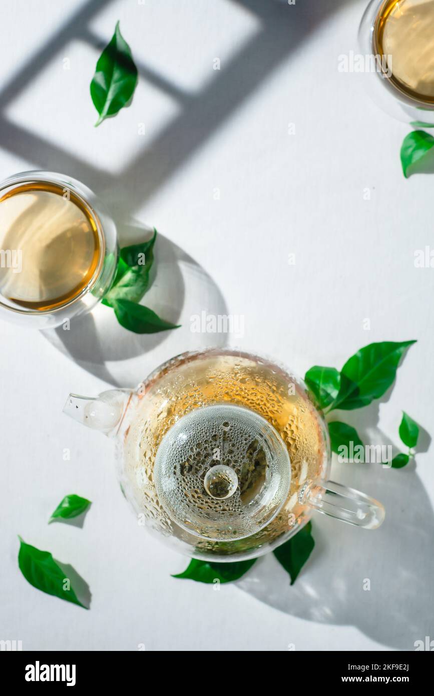 Tovaglia impeccabile, biancheria bianca con teiera in vetro e foglie di tè Foto Stock