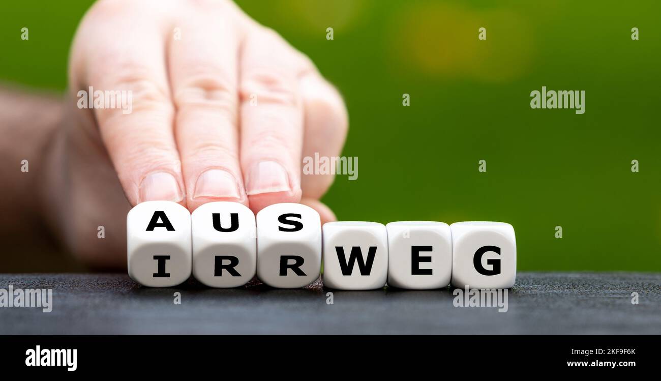 La mano gira i dadi e cambia la parola tedesca 'Irrweg' (sbagliato) in 'Ausweg' (uscita). Foto Stock