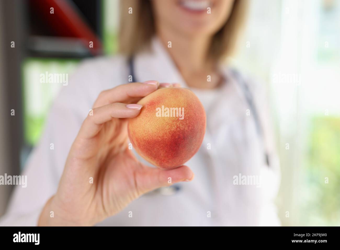 Medico femminile che tiene la pesca frutta in primo piano. Foto Stock