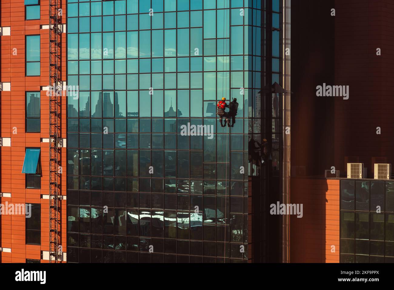 Alti lavoratori lavano la facciata e il vetro di un grattacielo Foto Stock