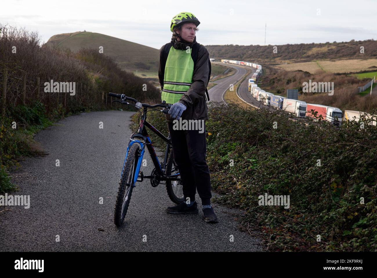 Ciclista guardando il traffico di camion che va al porto di dover sulla M20 Foto Stock