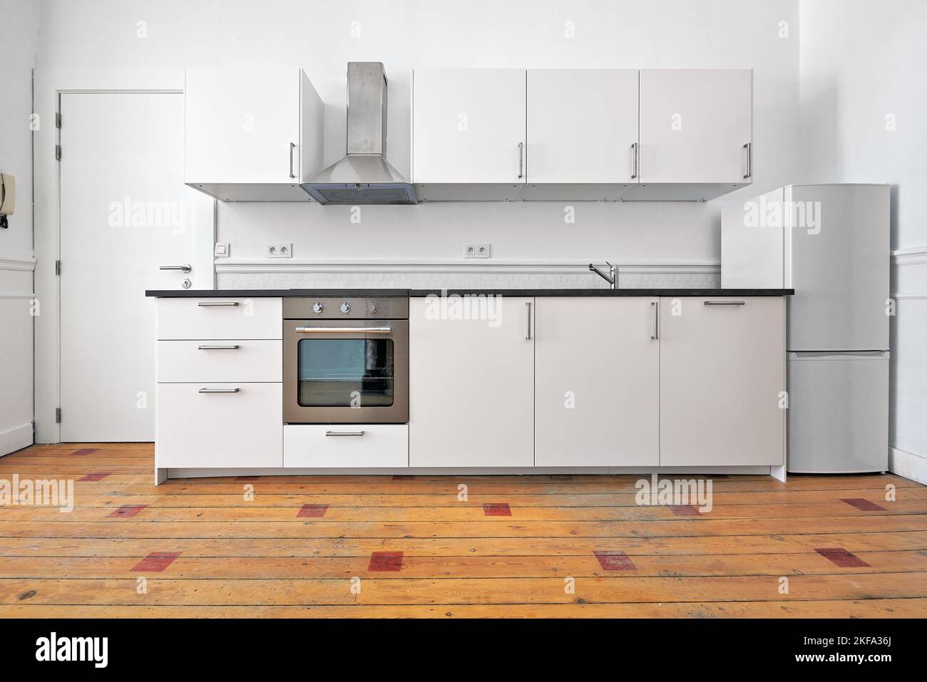 Appartamento vuoto con cucina moderna e pavimento in legno duro progettato dopo la ristrutturazione Foto Stock