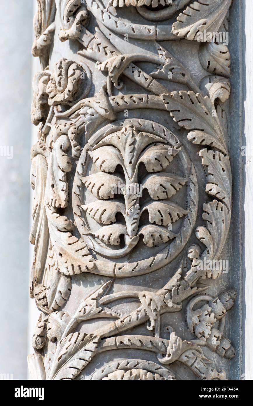 Primo piano sulle sculture floreali decorative scolpite su colonne di pietra della facciata esterna della chiesa cattolica italiana di Pisa Foto Stock