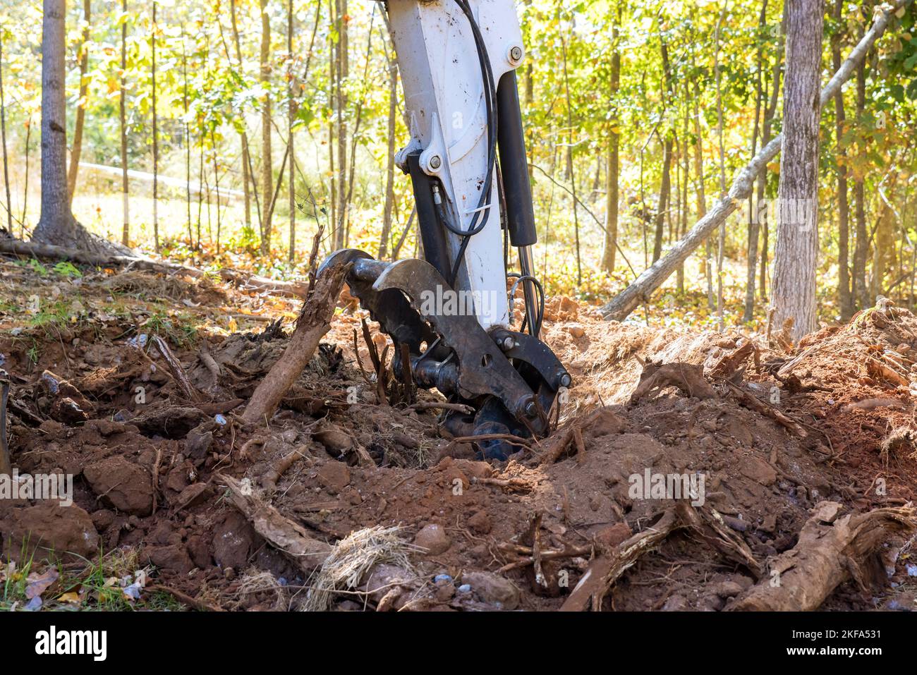 Con l'uso di trattori e minipale, il terreno è stato eliminato radici per preparare per lo sviluppo della suddivisione dell'alloggiamento Foto Stock