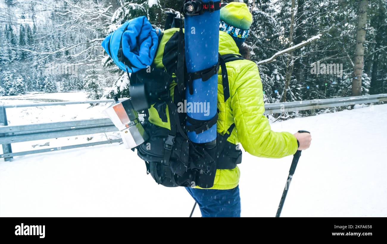 Uomo con zaino all'aperto che cammina in montagna in inverno. Backpacker escursioni nella foresta coperta di neve. Trekking invernale in montagna. Foto Stock