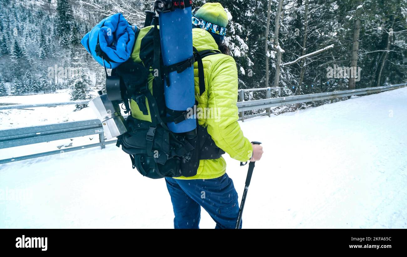 Uomo con zaino all'aperto che cammina in montagna in inverno. Backpacker escursioni nella foresta coperta di neve. Trekking invernale in montagna. Foto Stock
