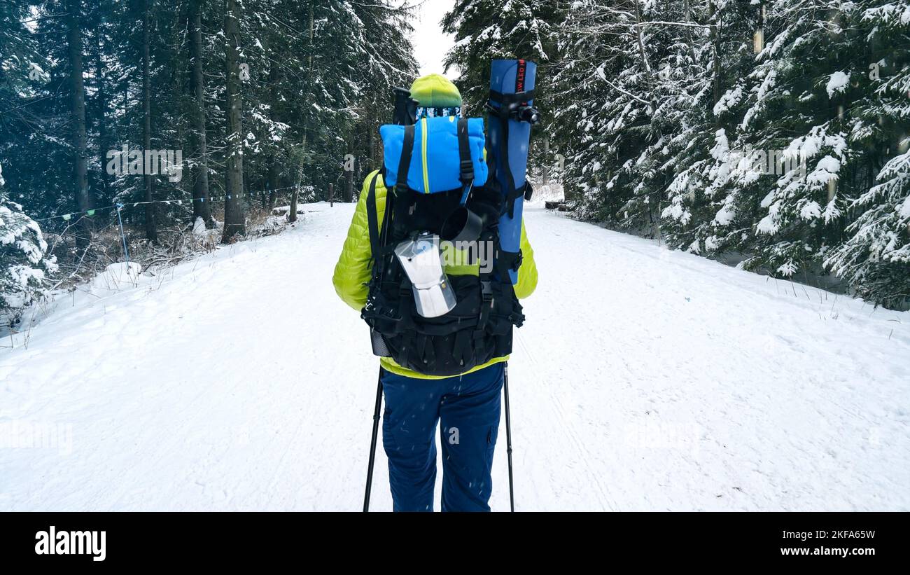 Uomo con zaino all'aperto che cammina in montagna in inverno. Backpacker escursioni nella foresta coperta di neve. Trekking invernale in montagna. Foto Stock