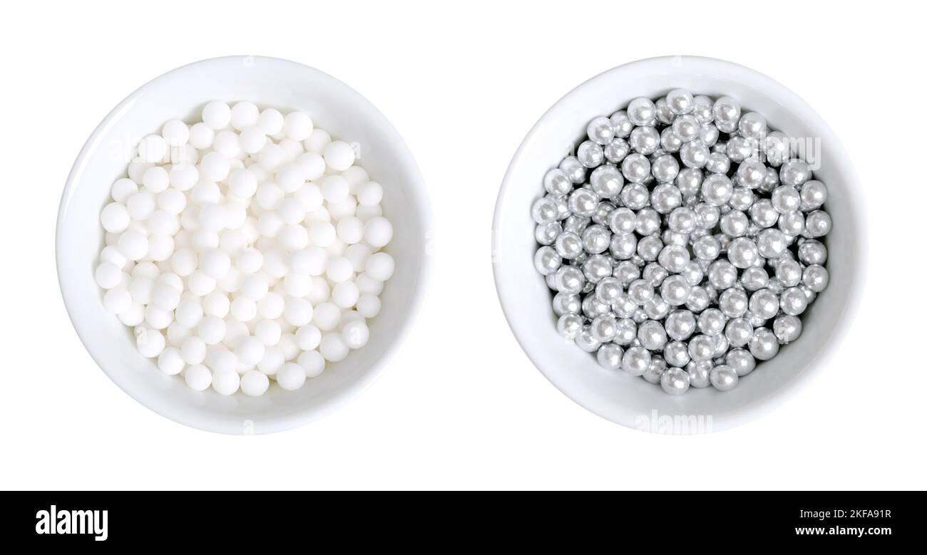 Perle di zucchero bianche e argentate per la decorazione, in ciotole bianche. Draghe commestibili e palle decorative, note anche come perle d'amore. Foto Stock