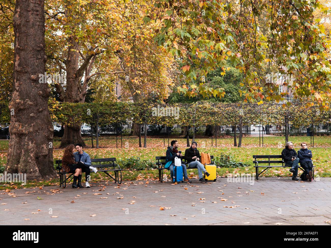 Russell Square London; persone sedute su panchine a Russell Square in autunno, Bloomsbury London UK Foto Stock