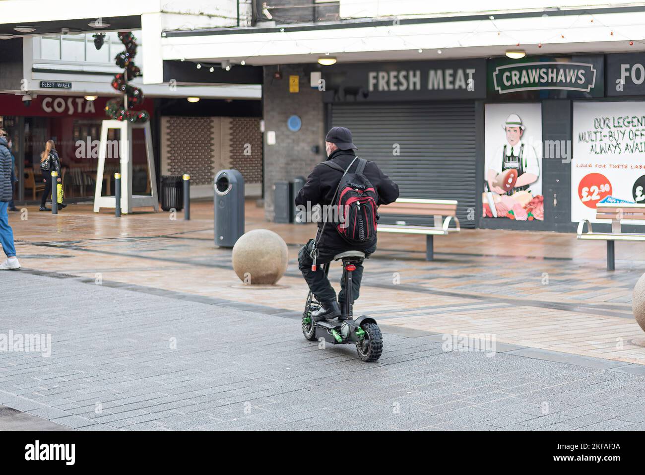 Uomo in sella a uno scooter elettrico sul marciapiede nel centro di Burnley. Foto Stock